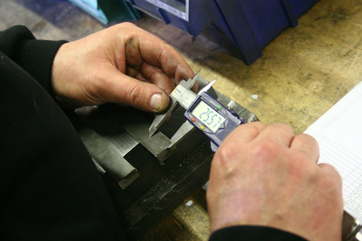 Digital caliper measuring a machined metal part for engineering review